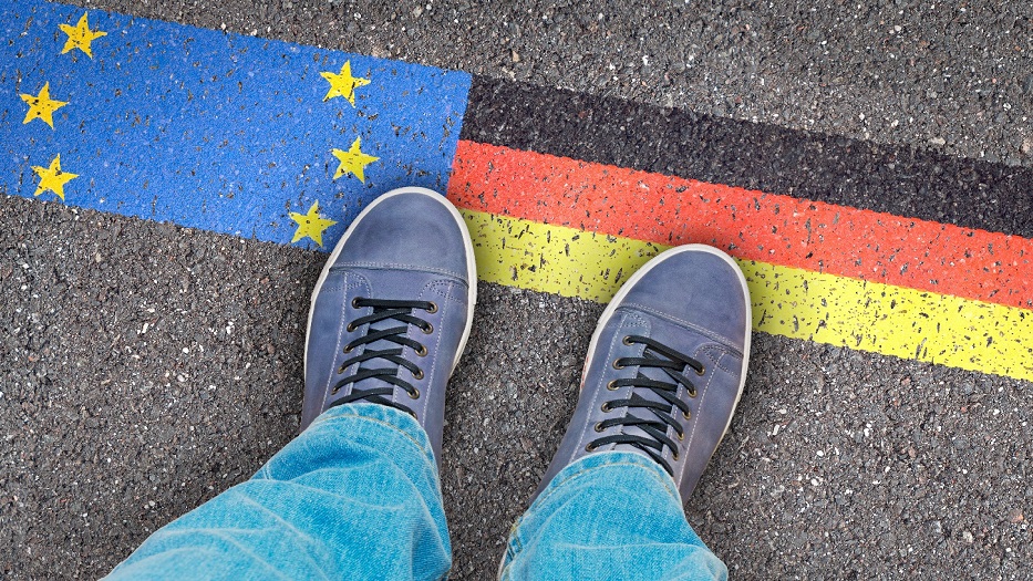 Schuhe stehen auf dem Asphalt auf dem eine EU und Deutschlandflagge zu sehen ist.