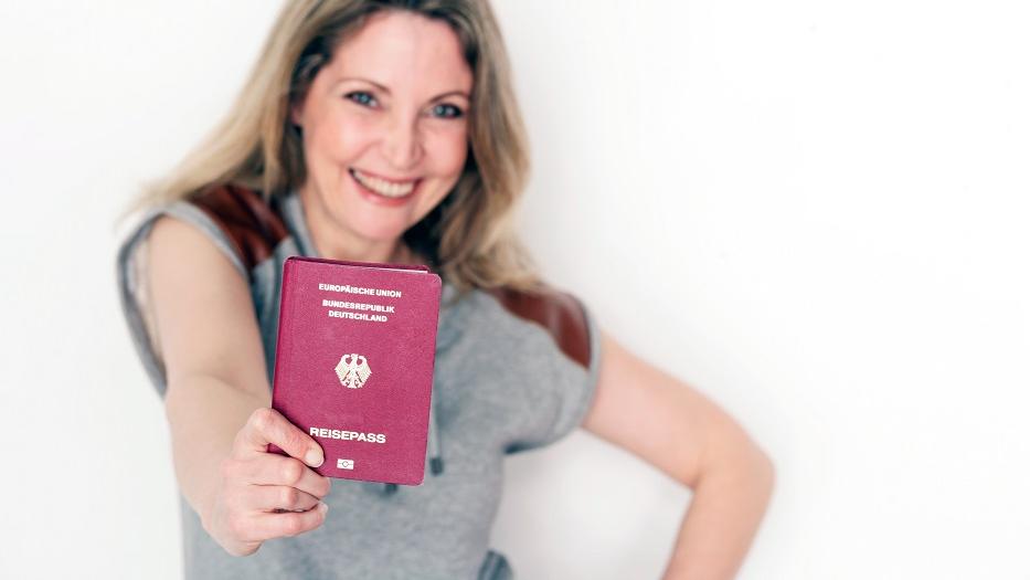 Frau hält einen Reisepass in die Kamera