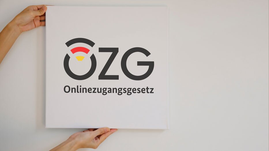 Logo OZG auf Leinwand, festgehalten von 2 Händen