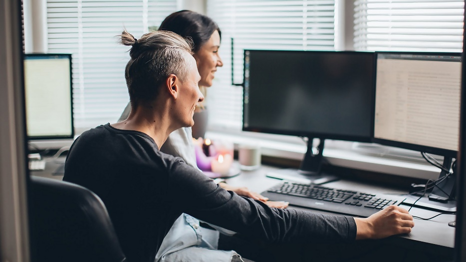Ein Mann und eine Frau sitzen vor einem PC. 